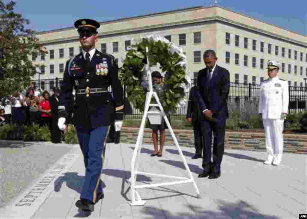 President Barack Obama and first lady Michelle Obama bow during a wreath laying to mark the 10th anniversary of the Sept. 11 attacks at the Pentagon in Washington, Sunday, Sept. 11, 2011. At right is Chairman of the Joint Chiefs of Staff Adm. Michael Mull