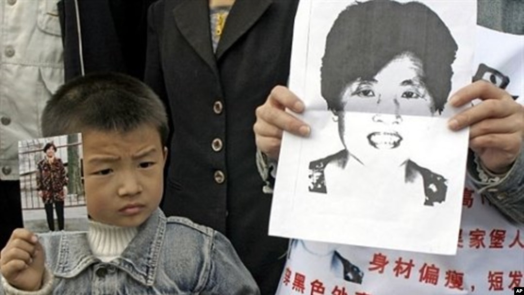 A young boy holds up a photo of his mother as he joins family members wearing posters describing the woman as missing from her home in Xian, northern China's Shaanxi province, as they launch a campaign to locate her (File Photo).