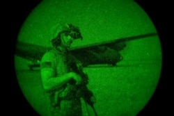 FILE - U.S. Army Spc. Dominic Deitrick, assigned to the 1-186th Infantry Battalion, seen through a night-vision device, provides security, June 12, 2020, at an undisclosed location in Somalia.