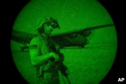 FILE - U.S. Army Spc. Dominic Deitrick, assigned to the 1-186th Infantry Battalion, seen through a night-vision device, provides security, June 12, 2020, at an undisclosed location in Somalia.