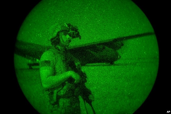FILE - U.S. Army Spc. Dominic Deitrick, assigned to the 1-186th Infantry Battalion, seen through a night-vision device, provides security, June 12, 2020, at an undisclosed location in Somalia.