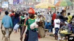 FILE - A man wearing a Cameroon soccer jersey walk past a busy Mokolo Market in Yaounde, Cameroon, Oct. 11, 2018. 