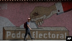 Un hombre camina frente a un mural del Poder Electoral en Caracas, el 31 de julio de 2024.