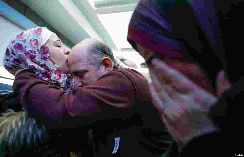 Syrian refugee Baraa Haj Khalaf (L) kisses her father Khaled as her mother Fattoum (R) cries after arriving at O'Hare International Airport in Chicago, Illinois, U.S.