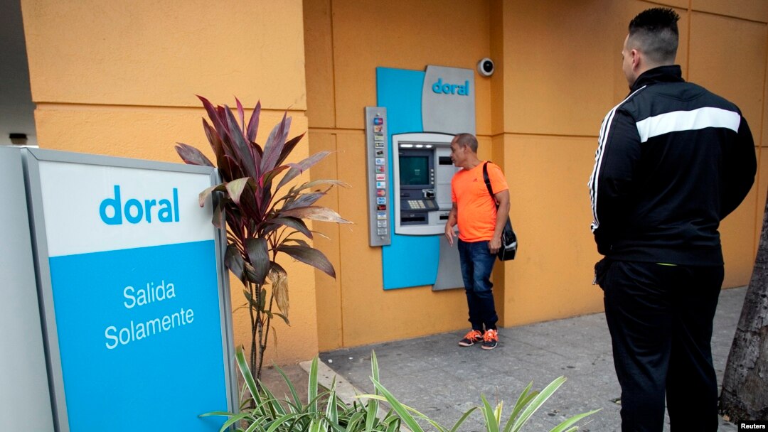 FILE - A man looks at the screen of an ATM of the failed Doral Bank in San Juan, Puerto Rico, February 27, 2015.