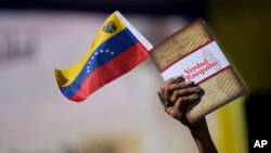 Una mujer sostiene una bandera venezolana y un libro sobre el Esequibo en Caracas, el pasado 29 de noviembre de 2023.