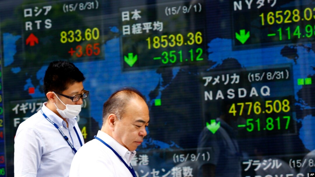 Men walk past an electronic stock indicator of a securities firm in Tokyo, Sept. 1, 2015. 