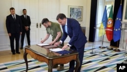 Ukrainian President Volodymyr Zelenskyy and Portuguese Prime Minister Luis Montenegro, right, sign bilateral agreements at the Sao Bento Palace, the premier's official residence, in Lisbon, May 28, 2024.