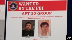 A poster displayed during a news conference at the Department of Justice in Washington, Thursday, Dec. 20, 2018, shows two Chinese citizens suspected to be with the group APT 10 carrying out an extensive hacking campaign to steal data from U.S. companies.