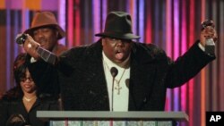 The Notorious BIG, qui a remporté le prix de l'artiste rap et du single rap de l'année, récupère ses prix sur le podium lors des Billboard Music Awards annuels à New York, le 6 décembre 1995. (Photo AP / Mark Lennihan, dossier)