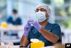 FILE - A technician prepares a Pfizer vaccine in the pharmacy area of the newly opened COVID-19 Vaccination Centre in Sydney, Australia, Monday, May 10, 2021. (James Gourley/Pool Photo via AP)