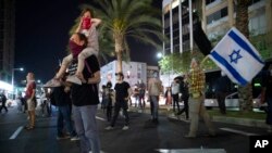 People wearing protective face masks and keep social distancing amid concerns over the country's coronavirus outbreak, take part in a protest against Prime Minister Benjamin Netanyahu in Tel Aviv, Israel, Sunday, April 19, 2020. 