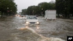 Heavy rainfall flooded the intersection of 15th Street and Constitution Ave., NW, stalling cars in the street, July 8, 2019, in Washington.
