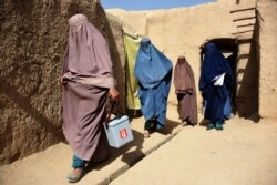 Afghan women wearing burqas from a polio immunization team walk together during a vaccination campaign in Kandahar, Oct. 15, 2019. Polio immunization is compulsory in Afghanistan, but distrust of vaccines is rife.