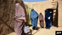 Afghan women wearing burqas from a polio immunization team walk together during a vaccination campaign in Kandahar, Oct. 15, 2019. Polio immunization is compulsory in Afghanistan, but distrust of vaccines is rife.