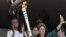 FILE - Brazil’s now-suspended President Dilma Rousseff holds the Olympic flame next to athlete Fabiana Claudino in Brasilia, Brazil, May 3, 2016.