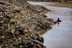 A man scavenges along a river for household plastic waste to be sold for recycling in Jakarta on Sept. 23, 2020.