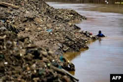 A man scavenges along a river for household plastic waste to be sold for recycling in Jakarta on Sept. 23, 2020.