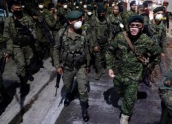 FILE - Filipino troopers wear protective masks as they arrive to augment police at Valenzuela, metropolitan Manila, Philippines, March 15, 2020.