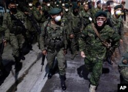 FILE - Filipino troopers wear protective masks as they arrive to augment police at Valenzuela, metropolitan Manila, Philippines, March 15, 2020.