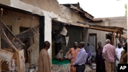 FILE - People inspect houses damaged in Saturday's rocket-propelled grenades by Islamic extremist in Maiduguri, Nigeria, May 31, 2015. 