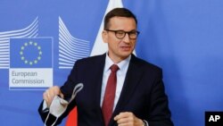 FILE - Poland's Prime Minister Mateusz Morawiecki takes off his protective mask as he arrives for a meeting with European Commission President Ursula von der Leyen at EU headquarters in Brussels, July 13, 2021. 