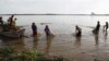 Cambodian fishermen move their fishing net from the Mekong River as they catch fish on the outskirts of Phnom Penh.