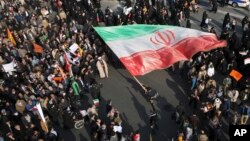 En esta foto proporcionada por la agencia de noticias Tasnim, un manifestante ondea una enorme bandera iraní durante las protestas en Mashad, Iran, el jueves 4 de enero.