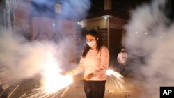 A girl plays with fireworks during Diwali, the Hindu festival of lights, in Jammu, India, Nov. 14, 2020. 