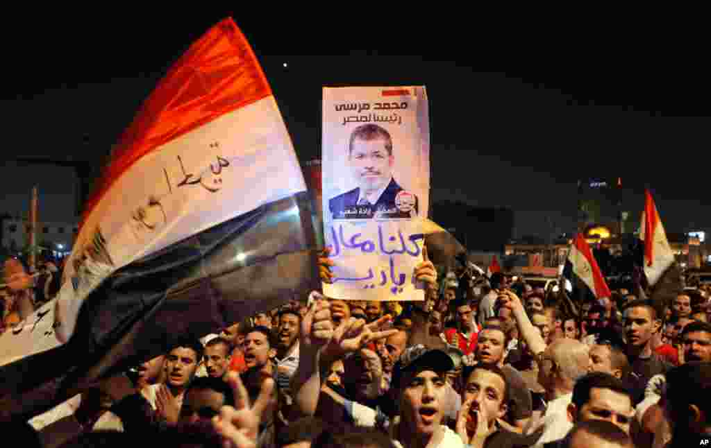 Thousands of supporters celebrate with posters showing Egypt's President Mohamed Morsi in Tahrir Square, late Sunday, Aug. 12, 2012. Morsi ordered the retirement of the defense minister and chief of staff. Arabic reads: "We are all with you."