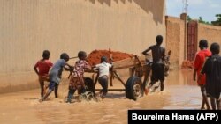 Des enfants transportent de la latérite sur un chariot pour construire des barrages afin d'arrêter les eaux du fleuve Niger à Niamey le 3 septembre 2019.