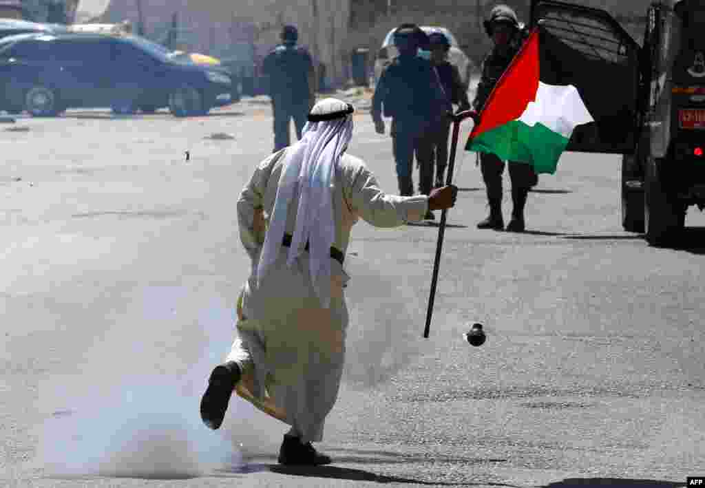 A Palestinian demonstrator runs past a tear gas canister launched by Israeli forces in the occupied West Bank during a protest in solidarity with Palestinian prisoners.