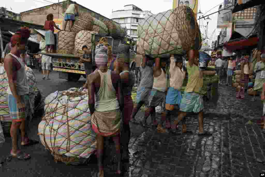 Indian laborers carry a giant basket of vegetables to a wholesale market in Kolkata. 