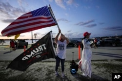 Trang Le of Orlando, right, and Maria Korynsel of North Palm Beach show their support for former President Donald Trump after the news broke that Trump has been indicted by a Manhattan grand jury, Thursday, March 30, 2023, near Trump's Mar-a-Lago estate in Palm Beach, Fla. (AP Photo/Rebecca Blackwell)