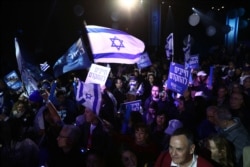Blue and White party supporters hold banners and flags during an election campaign rally in Tel Aviv, Feb. 29, 2020. The Hebrew writing say " Must to advance."