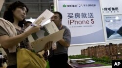 A real estate agent explains property development details to a woman during the China Property and Investment Show in Beijing, September 21, 2012.