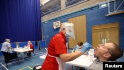 FILE - A health worker takes a swab from a man for a COVID-19 test at a Stoke-on-Trent City Council facility at Fenton Manor Sports Complex in Fenton, Stoke-on-Trent, Britain Oct. 6, 2020. (Reuters)