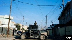 FILE - A member of the Iraqi special forces' Counter-Terrorism Service (CTS) stands on the top of a Humvee as demining experts search for booby-trapped buildings in eastern Mosul, Iraq, Jan. 16, 2017.