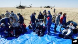 In this handout photo by the Roscosmos space agency, U.S. astronauts Andrew Morgan, left, Jessica Meir, right, and Russian cosmonaut Oleg Skripochka sit shortly after landing in a Soyuz MS-15 space capsule near Dzhezkazgan, Kazakhstan, April 17, 2020.