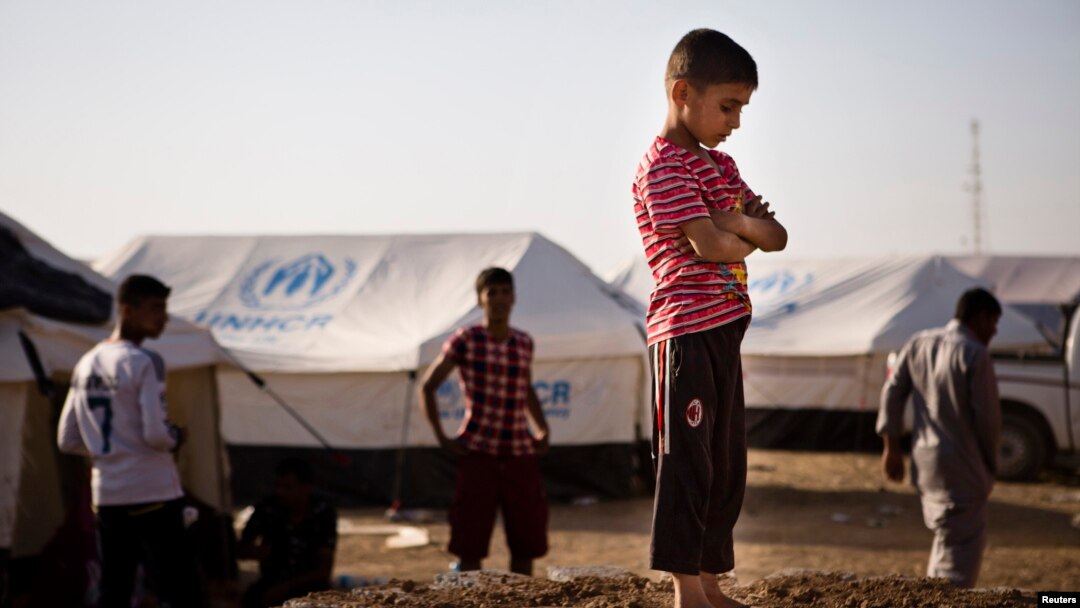 A boy, who fled from the violence in Mosul, stands near tents in a camp for internally displaced people on the outskirts of Erbil in Iraq's Kurdistan region, June 14, 2014. 