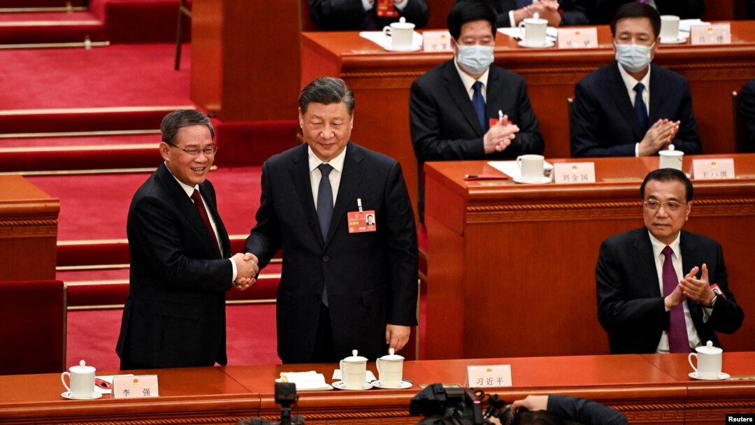 El presidente de China, Xi Jinping (centro), da la mano al recién elegido primer ministro Li Qiang (izquierda) mientras el exprimer ministro Li Keqiang (derecha) aplaude durante la cuarta sesión plenaria de la Asamblea Popular Nacional (APN), en Beijing, el 11 de marzo de 2023.