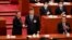 El presidente de China, Xi Jinping (centro), da la mano al recién elegido primer ministro Li Qiang (izquierda) mientras el exprimer ministro Li Keqiang (derecha) aplaude durante la cuarta sesión plenaria de la Asamblea Popular Nacional (APN), en Beijing, el 11 de marzo de 2023.