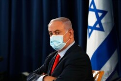 FILE - Israeli Prime Minister Benjamin Netanyahu wears a mask as he looks on during the weekly cabinet meeting in Jerusalem, May 31, 2020.