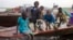 A group of displaced brothers and sisters cautiously disembark from a boat that has just carried them across the Nile to a village in Awerial, which has received tens of thousands of displaced people who crossed the Nile river by boat to flee the recent f