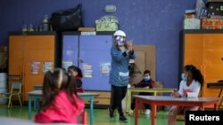 Una maestra camina en un salón de clases con estudiantes manteniendo el distanciamiento social en una escuela pública, luego de la reactivación de clases presenciales, en medio de un brote de la enfermedad coronavirus (COVID-19), en Bogotá, Colombia, el 15 de febrero de 2021.