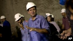 FILE - Rio de Janeiro's Mayor Eduardo Paes, center, talks with the media inside the Expressway Tunnel in Rio de Janeiro, Brazil, March 24, 2015.