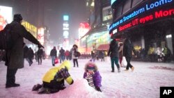 Unos niños hacen una montaña de nieve en Times Square, Nueva York, durante la tormenta de nieve.