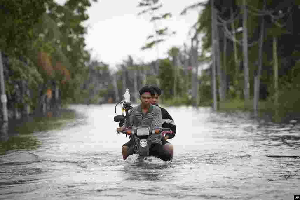 Residents ride on a self-modified motorcycle through a road covered by floodwaters in Tumpat, on the outskirts of Kota Bahru, Malaysia.