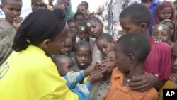 FILE - A World Health Organization (WTO) official gives a dose of polio vaccine to Somali children in Tosweyn village, in the Baidoa region, Somalia, Sept. 12, 2000. 