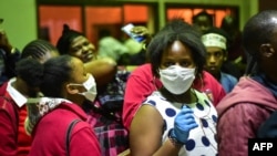 FILE - Travelers wearing face masks as protective measure wait to get their temperature checked at the border post with Kenya in Namanga, northern Tanzania, on March 16, 2020, on the day Tanzania confirmed the first case of COVID-19. 